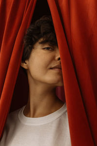 Close-up portrait of woman by red curtain