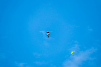 Low angle view of paragliding against blue sky