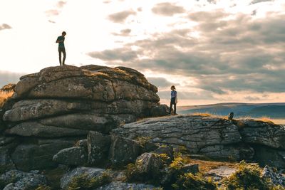Man and woman standing on cliff against sky