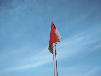 Low angle view of indonesia flag against blue sky