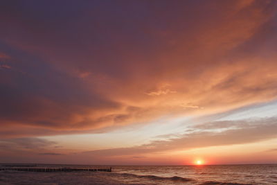 Scenic view of sea against dramatic sky during sunset