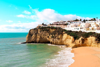 Scenic view of sea by buildings against sky