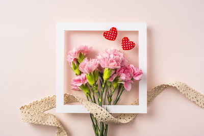 Directly above shot of pink flower on table against white background