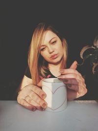 Close-up of young woman with hand in black background