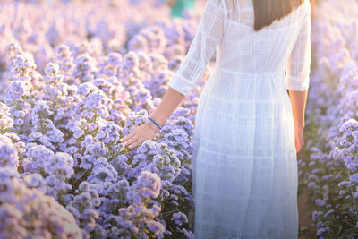 Midsection of woman standing by flowering plants