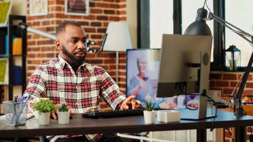 Portrait of young woman using laptop at desk in office