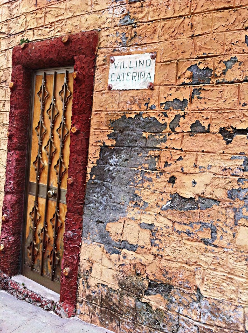 text, architecture, communication, built structure, building exterior, wall - building feature, brick wall, western script, wall, door, old, sign, outdoors, non-western script, day, weathered, capital letter, brick, stone wall, no people