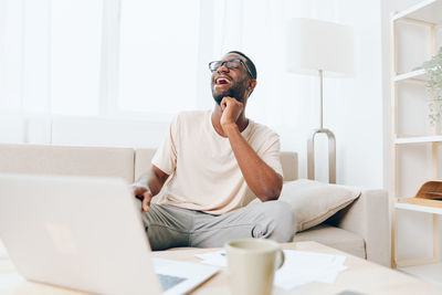 Young man using laptop while sitting on sofa at home