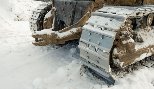 The metal tracks of a bulldozer tractor in winter clears the road from snow. on a frosty day