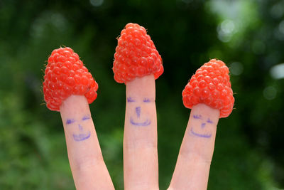 Close-up of hand holding strawberry against blurred background