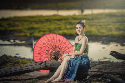 Side view of woman sitting on log