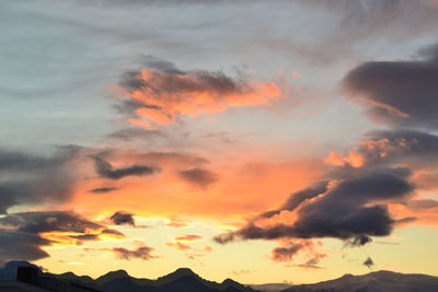 Scenic view of mountains against cloudy sky at sunset