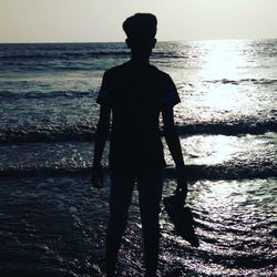 Rear view of silhouette man standing at beach