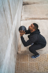 Side view of man exercising while standing against wall