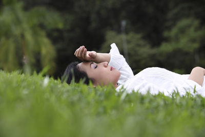 Woman lying on grassy field at park