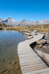 Scenic view of lake and mountains against clear blue sky