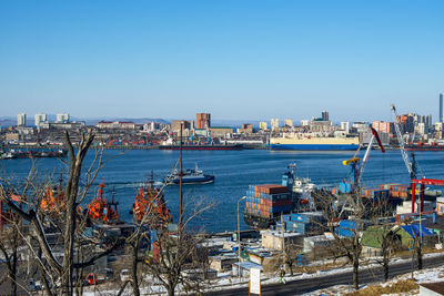 Sailboats in city by sea against clear blue sky