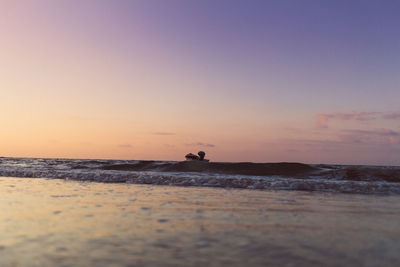 Silhouette man riding on beach against sky during sunset