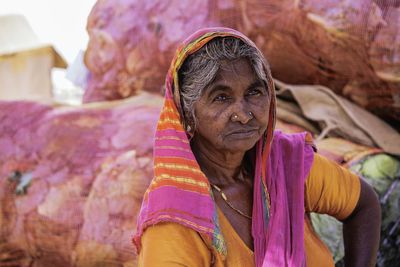 Thoughtful woman in sari sitting against sacks