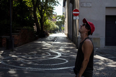 Side view of young woman standing on street in city