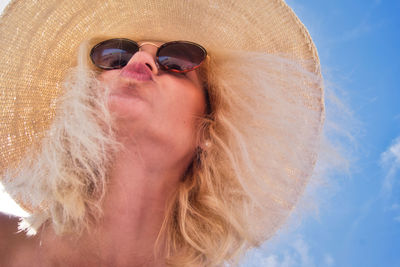 Low angle view of young woman wearing sunglasses against sky