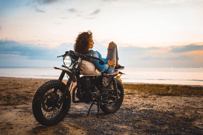 Rear view of person riding motorcycle on beach