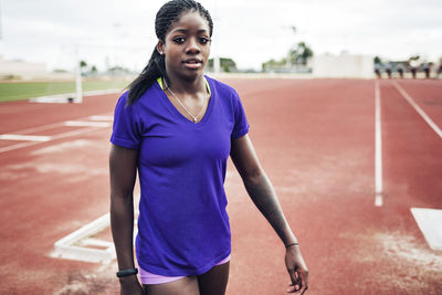 Portrait of confident sportswoman walking on running tracks