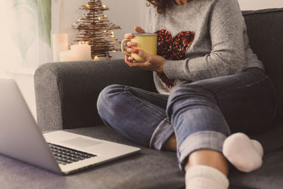 Midsection of man using mobile phone while sitting on sofa at home