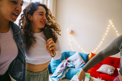 Woman holding hairbrush singing with teenage friend at home