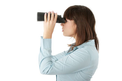 Side view of woman photographing against white background