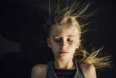 Overhead view of girl with eyes closed and tousled hair during sunny day