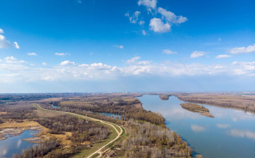 Aerial view of road amidst land against blue sky