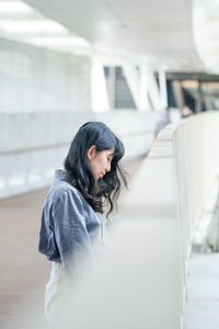 Young woman standing against white wall