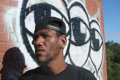 Close-up of man looking away by brick wall