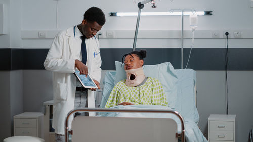 Doctor showing digital tablet to patient at hospital