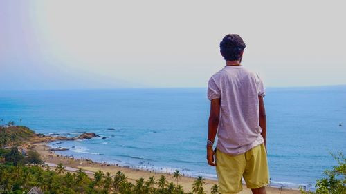 Rear view of man looking at sea against sky