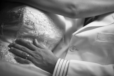 Midsection of bride and groom embracing