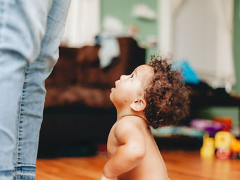 Cute boy looking up at mother sitting at home