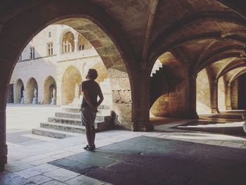 Rear view of man walking in corridor of historic building