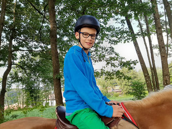 Portrait of smiling young man sitting against trees