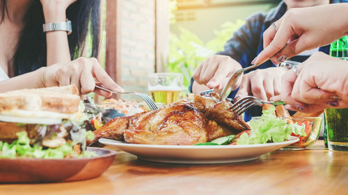 Midsection of people having roasted chicken