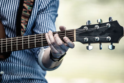 Midsection of man playing guitar outdoors