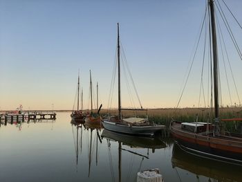 Boats moored in harbor at sunset