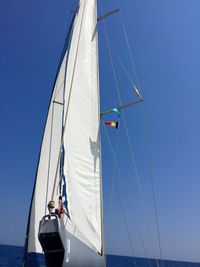 Sailboat sailing on sea against clear blue sky