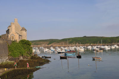 Boats moored in canal by buildings against sky