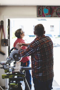 Senior couple standing by circular saw in workshop