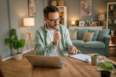 Young man using laptop while sitting on table