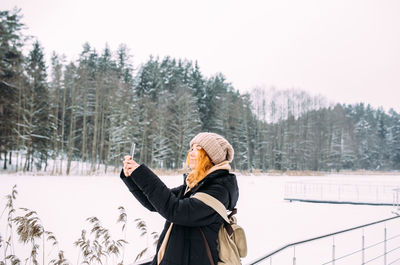 Rear view of woman standing against trees