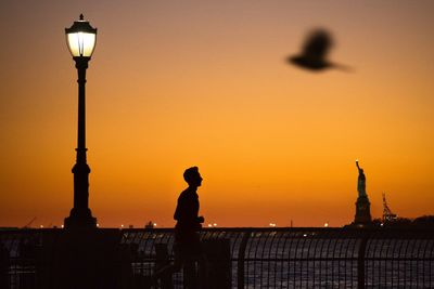 Silhouette people by sea against sky during sunset