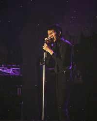 Full length of man holding umbrella standing at night